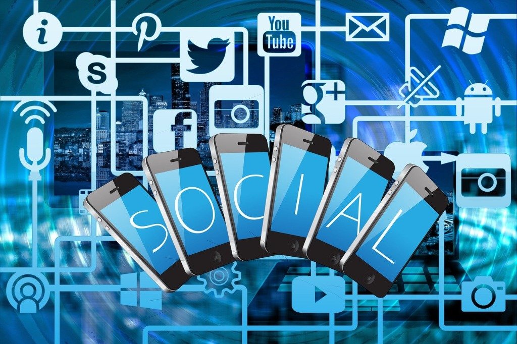 Stock illustration of smartphones spelling out SOCIAL surrounded by social media platform icons over a city skyline